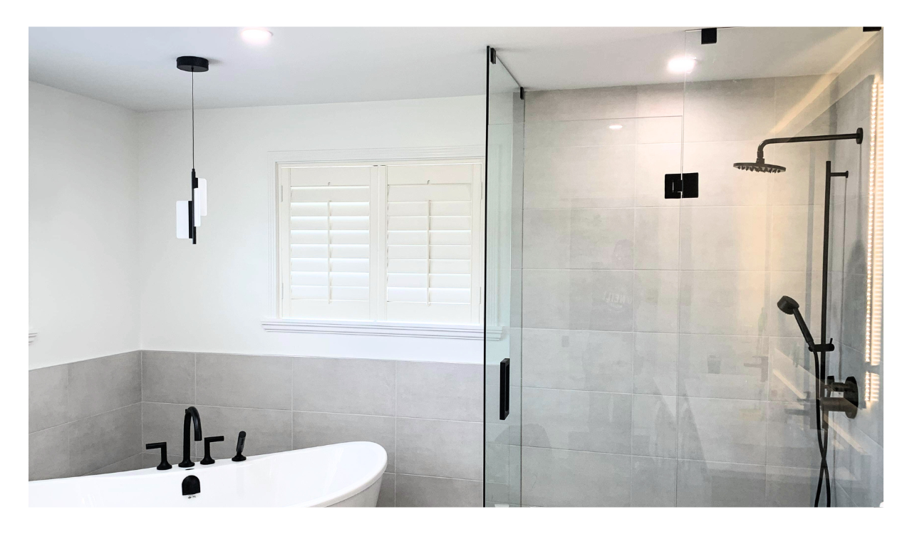 Spacious bathroom with stand alone tub, glass shower and black fixtures.